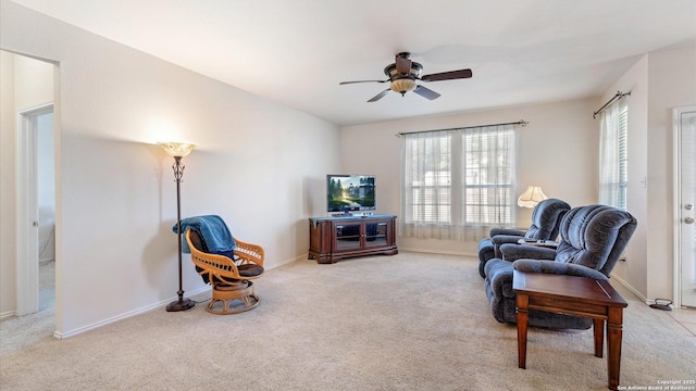 living area with plenty of natural light, light colored carpet, and ceiling fan