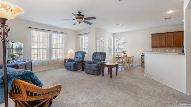 sitting room featuring a healthy amount of sunlight, light colored carpet, and ceiling fan