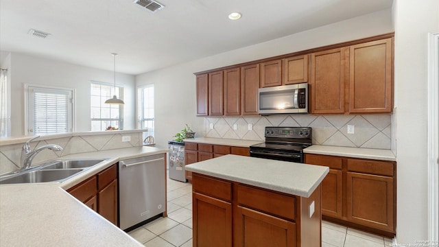 kitchen featuring light tile patterned flooring, appliances with stainless steel finishes, pendant lighting, tasteful backsplash, and sink