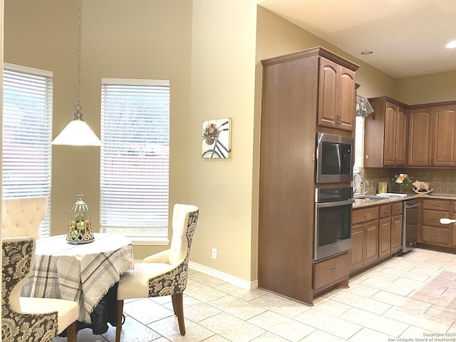 kitchen featuring pendant lighting, sink, built in microwave, decorative backsplash, and oven