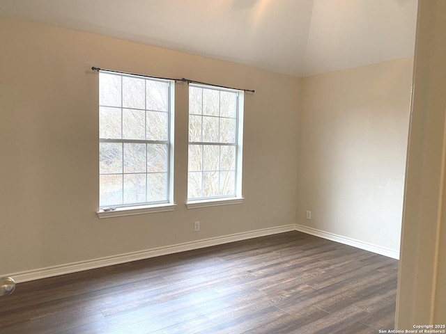 spare room with dark hardwood / wood-style flooring, a wealth of natural light, and vaulted ceiling