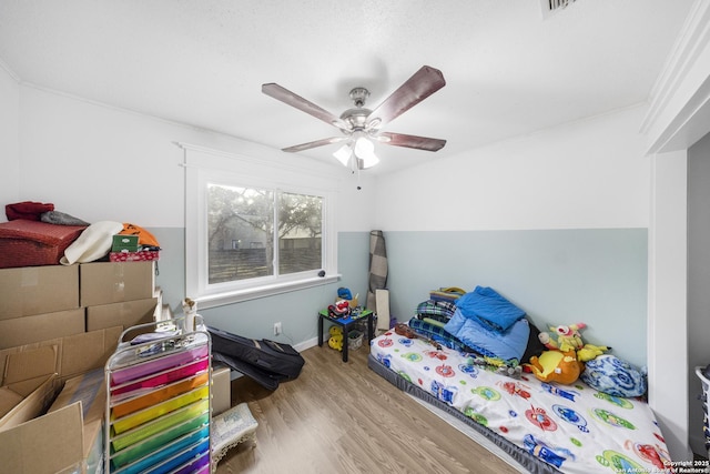 bedroom with ornamental molding, ceiling fan, and light hardwood / wood-style floors