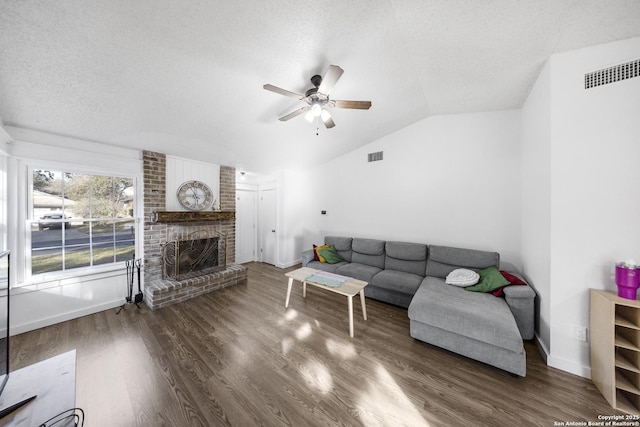 living room with a fireplace, lofted ceiling, dark hardwood / wood-style flooring, ceiling fan, and a textured ceiling