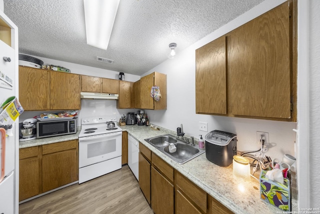 kitchen featuring sink, white appliances, light hardwood / wood-style flooring, and a textured ceiling