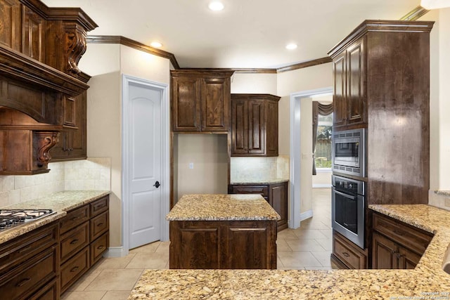 kitchen with crown molding, stainless steel appliances, tasteful backsplash, light stone countertops, and a kitchen island