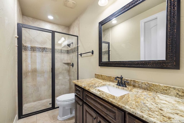 bathroom featuring tile patterned flooring, vanity, toilet, and walk in shower