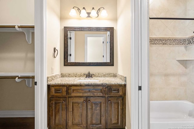 bathroom with tiled shower / bath combo, vanity, and wood-type flooring