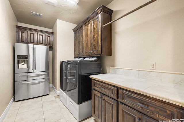 laundry area featuring washer and clothes dryer, cabinets, and light tile patterned flooring