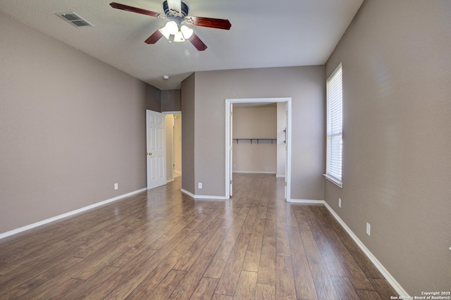 unfurnished bedroom with ceiling fan, a spacious closet, dark hardwood / wood-style flooring, and a closet