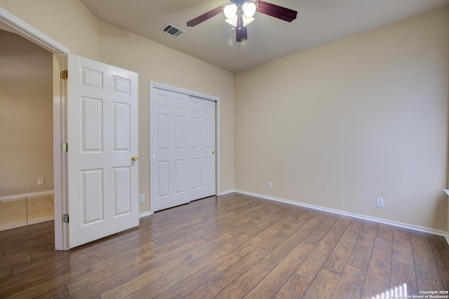 unfurnished bedroom featuring dark wood-type flooring, ceiling fan, and a closet