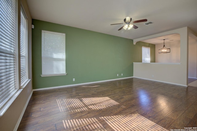 spare room featuring dark hardwood / wood-style floors and ceiling fan with notable chandelier