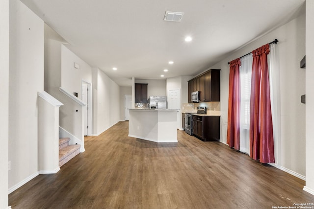 kitchen with dark wood-type flooring, dark brown cabinetry, stainless steel appliances, and a center island