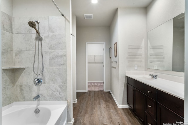 bathroom with vanity, hardwood / wood-style flooring, and tiled shower / bath