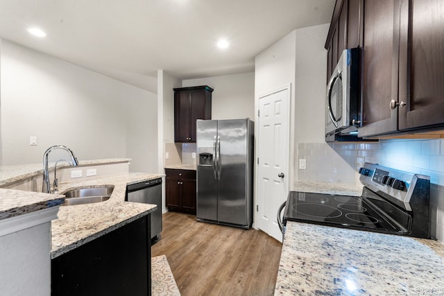 kitchen featuring sink, light stone counters, tasteful backsplash, light hardwood / wood-style flooring, and appliances with stainless steel finishes