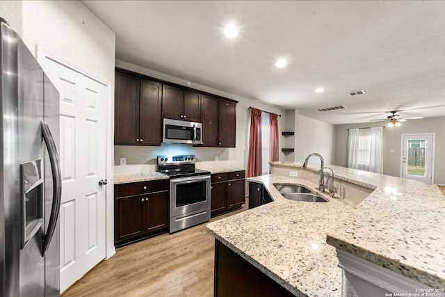 kitchen featuring light stone counters, sink, stainless steel appliances, and an island with sink