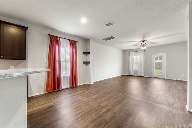 unfurnished living room with dark wood-type flooring, ceiling fan, and a textured ceiling