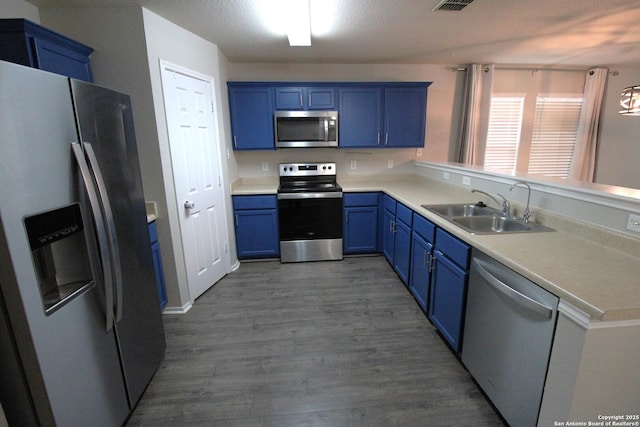 kitchen featuring sink, blue cabinetry, dark hardwood / wood-style floors, and appliances with stainless steel finishes