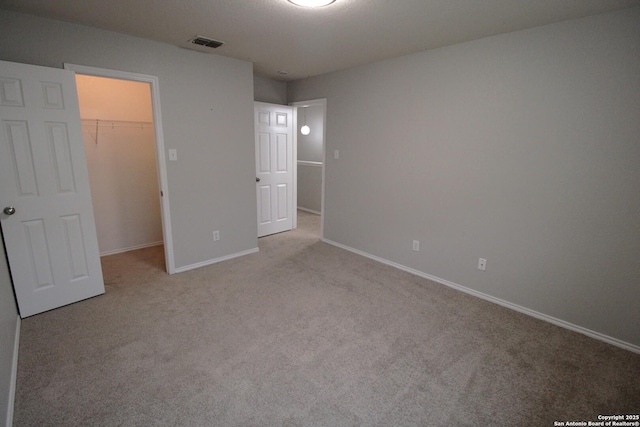 unfurnished bedroom featuring a spacious closet, light carpet, and a closet