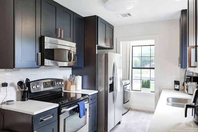 kitchen featuring stainless steel appliances, light stone counters, independent washer and dryer, and decorative backsplash