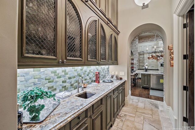 bar featuring sink, dark brown cabinets, light stone countertops, and dishwasher