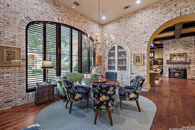 dining space featuring hardwood / wood-style floors, a large fireplace, and brick wall