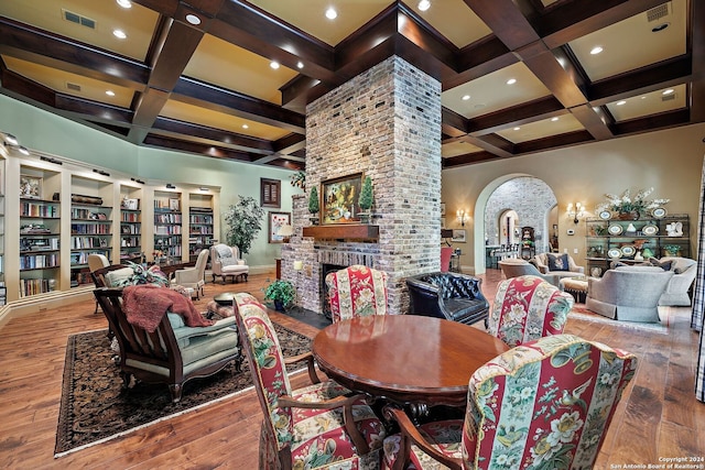 dining area featuring beamed ceiling, coffered ceiling, a fireplace, and hardwood / wood-style floors