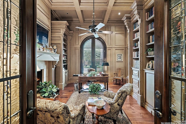 office area featuring built in shelves, coffered ceiling, light hardwood / wood-style flooring, and wood walls