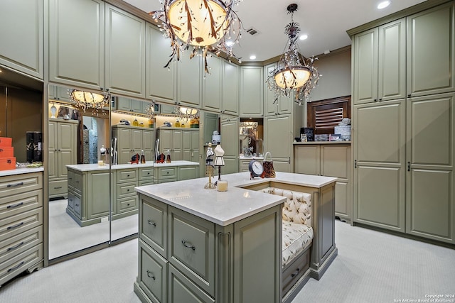 kitchen featuring light carpet, a kitchen island with sink, green cabinets, and decorative light fixtures