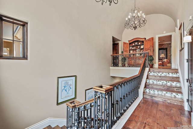 stairs featuring hardwood / wood-style flooring, a chandelier, and vaulted ceiling