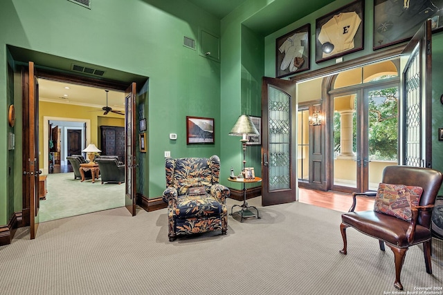 sitting room with french doors, ornamental molding, light carpet, and a high ceiling