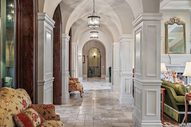 hall featuring vaulted ceiling and ornate columns