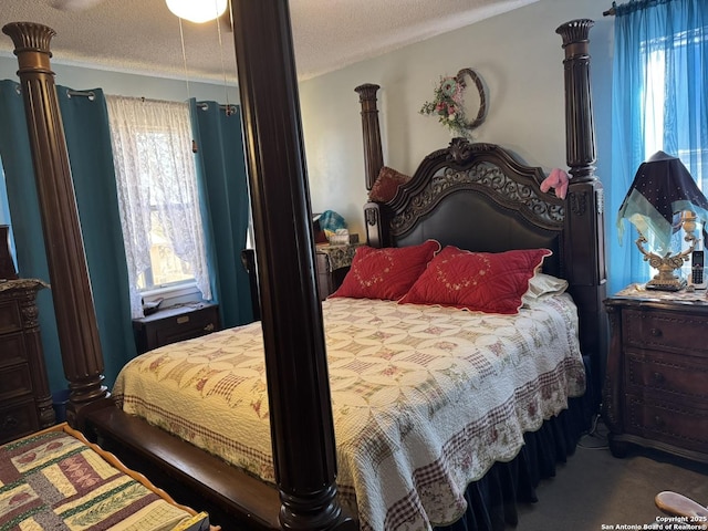 carpeted bedroom featuring ornate columns and a textured ceiling