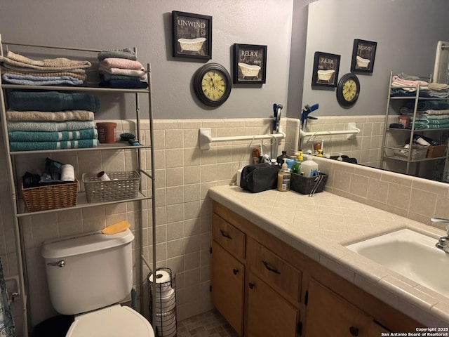 bathroom featuring vanity, toilet, and tile walls