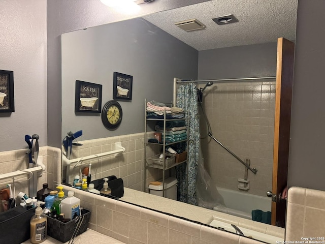 bathroom featuring shower / bath combination with curtain, tile walls, toilet, and a textured ceiling