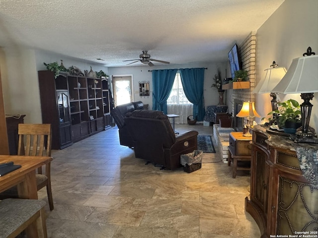 living room with ceiling fan, a brick fireplace, and a textured ceiling