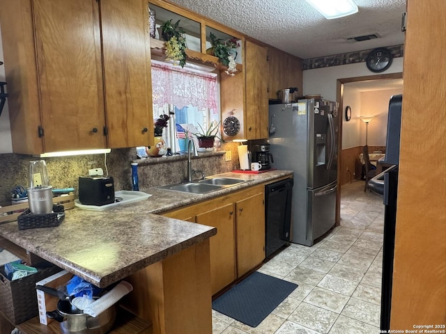 kitchen with sink, stainless steel fridge, backsplash, black dishwasher, and a textured ceiling