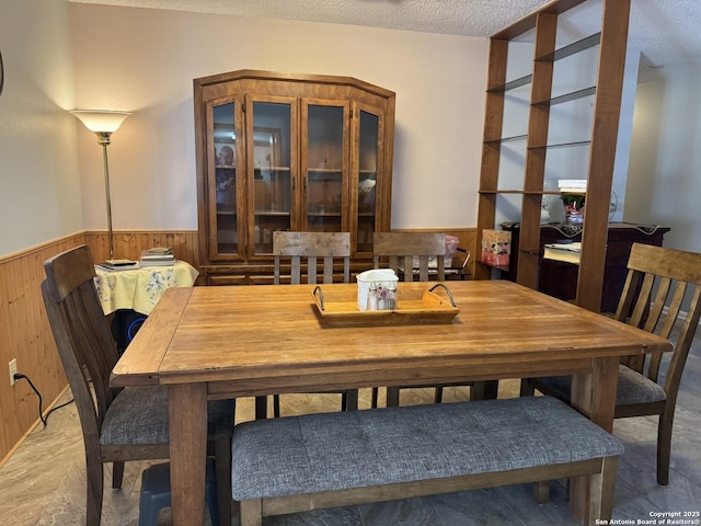 dining room featuring wooden walls and a textured ceiling