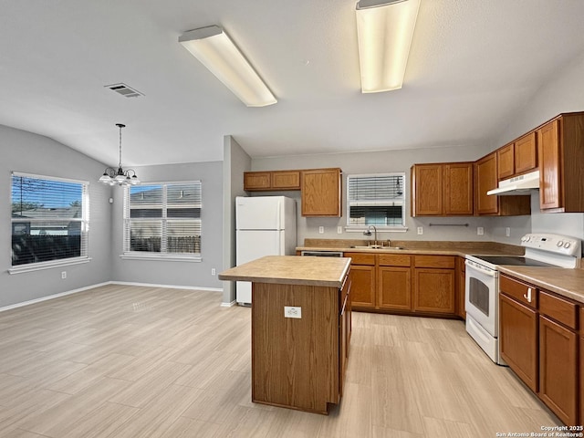 kitchen featuring vaulted ceiling, decorative light fixtures, sink, a center island, and white appliances