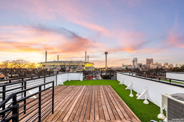 deck at dusk with central AC unit and a lawn