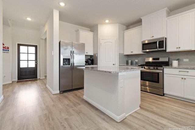 kitchen featuring stainless steel appliances, light stone countertops, a kitchen island, and white cabinets