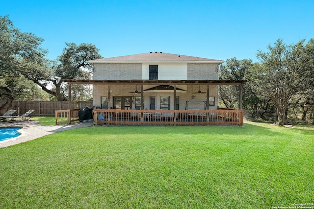 rear view of property with ceiling fan, a patio area, and a lawn