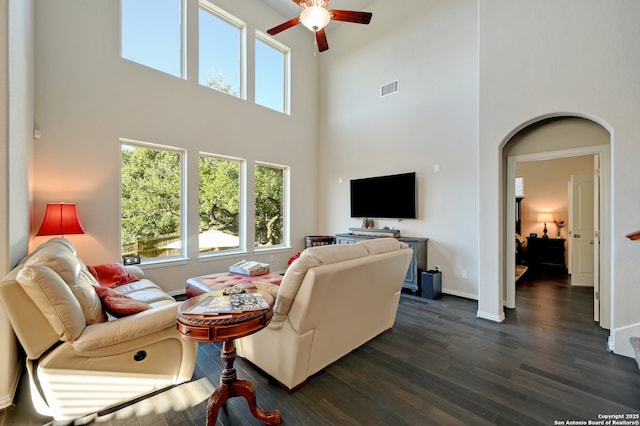 living room featuring a high ceiling, dark wood-type flooring, and ceiling fan