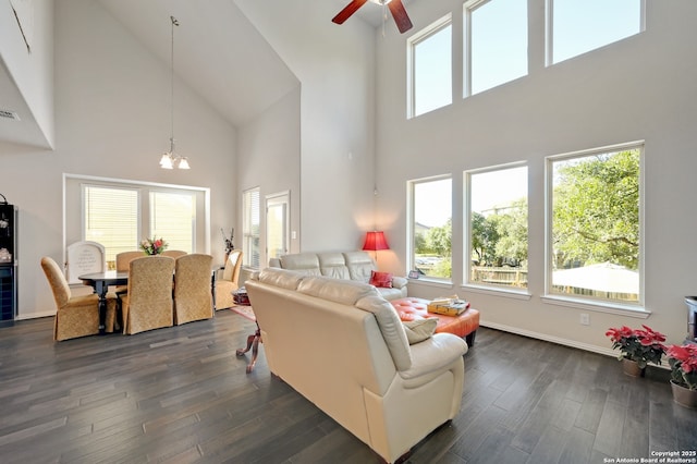 living room featuring a high ceiling, dark wood-type flooring, and ceiling fan with notable chandelier