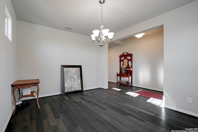 spare room with an inviting chandelier and dark hardwood / wood-style floors