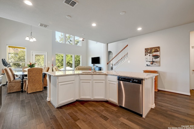 kitchen with white cabinetry, decorative light fixtures, an island with sink, and dishwasher