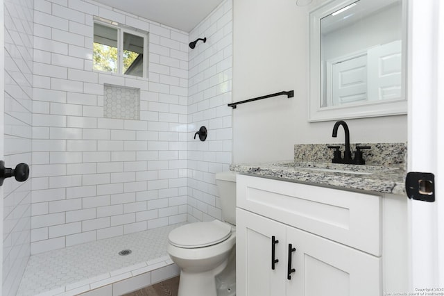 bathroom featuring vanity, toilet, and a tile shower