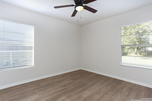 unfurnished room featuring ceiling fan, dark hardwood / wood-style floors, and a wealth of natural light