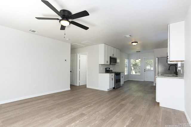 kitchen featuring sink, white cabinets, backsplash, stainless steel appliances, and light wood-type flooring