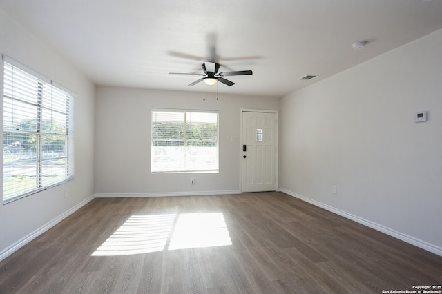 empty room featuring dark wood-type flooring and ceiling fan