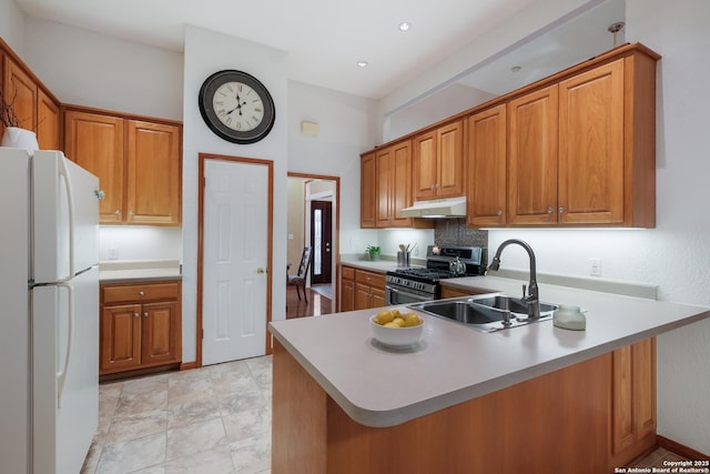 kitchen featuring sink, gas stove, kitchen peninsula, and white fridge